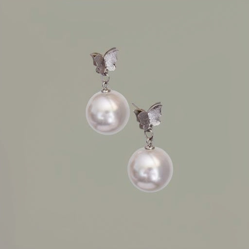 Pearl earrings with butterfly accents on a light green background